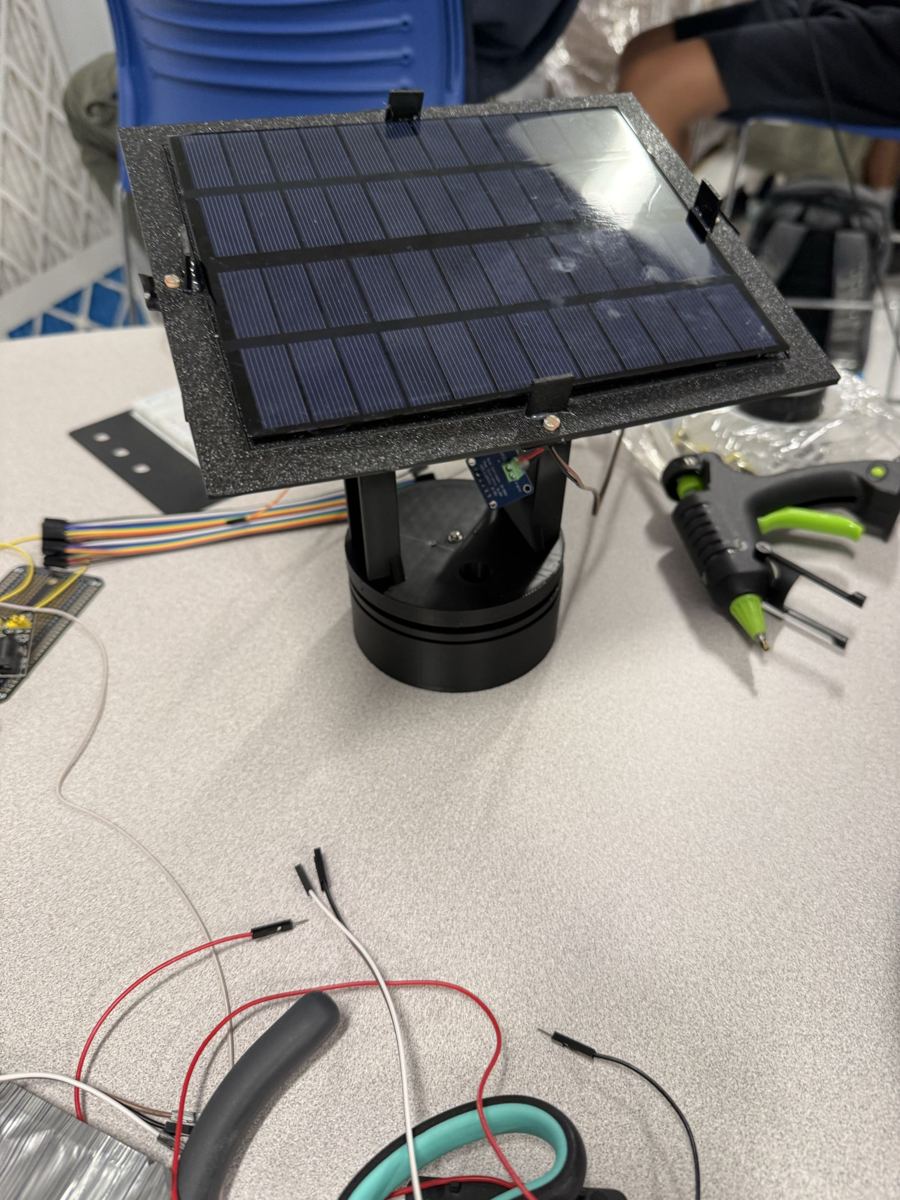 The tracker with a black base, partway through assembly, next to a glue gun